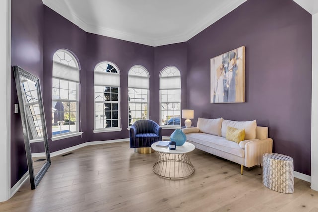 living area with light hardwood / wood-style flooring and ornamental molding