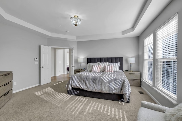 bedroom with carpet, a raised ceiling, and multiple windows