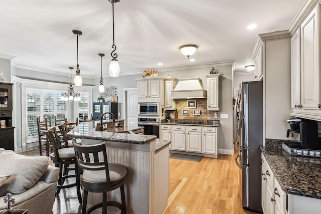 kitchen featuring pendant lighting, a breakfast bar, premium range hood, sink, and stainless steel appliances