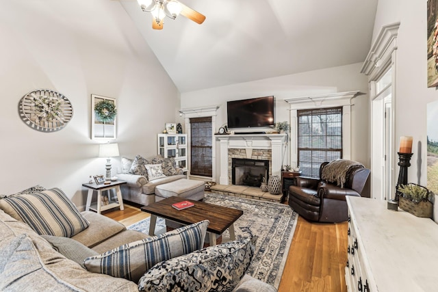 living room featuring lofted ceiling, ceiling fan, light wood-type flooring, and a fireplace