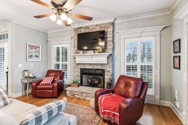 living room featuring hardwood / wood-style floors, a stone fireplace, and crown molding