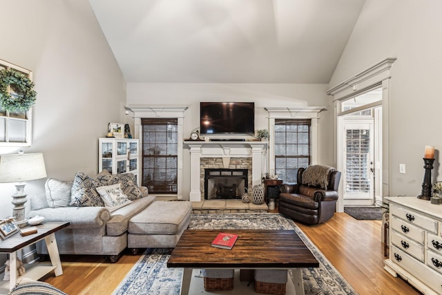 living room featuring a fireplace, light hardwood / wood-style floors, and vaulted ceiling