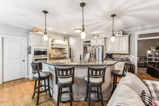 kitchen featuring appliances with stainless steel finishes, tasteful backsplash, a breakfast bar, decorative light fixtures, and dark stone countertops