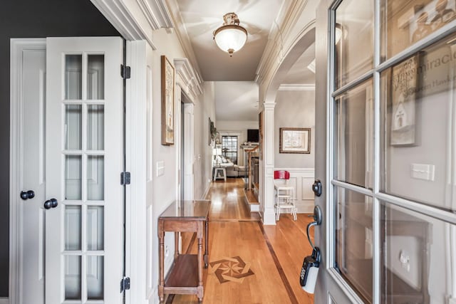 hallway featuring light hardwood / wood-style floors, ornate columns, and ornamental molding