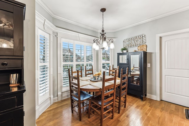 dining space featuring a chandelier, light hardwood / wood-style floors, and crown molding