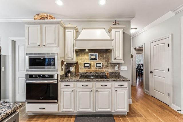 kitchen featuring crown molding, decorative backsplash, light hardwood / wood-style floors, custom range hood, and stainless steel appliances