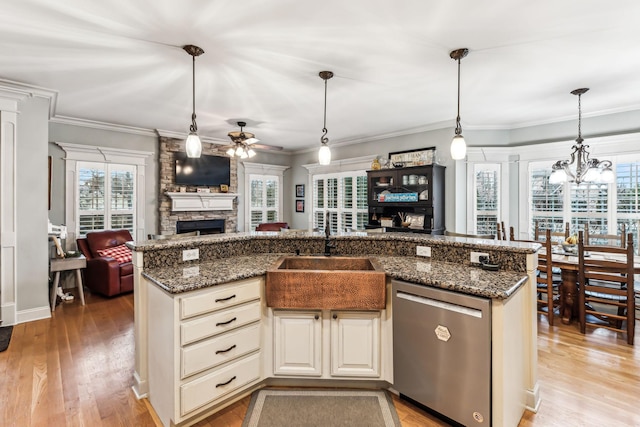 kitchen featuring dishwasher, ceiling fan with notable chandelier, sink, hanging light fixtures, and a fireplace