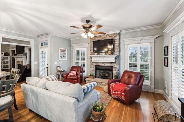 living room featuring a fireplace, hardwood / wood-style floors, ceiling fan, and crown molding