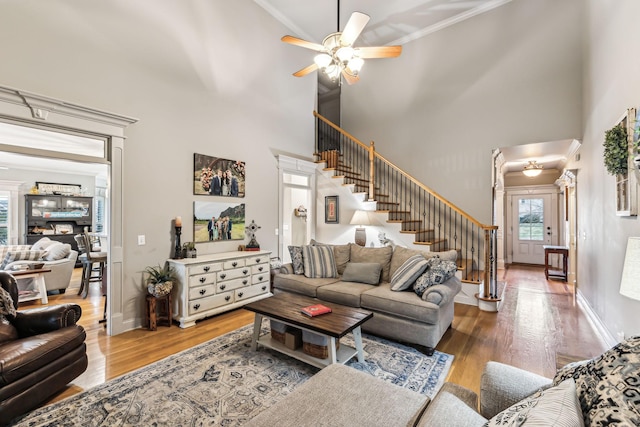 living room featuring crown molding, ceiling fan, a high ceiling, and hardwood / wood-style flooring