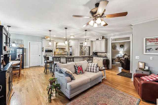 living room with ceiling fan, light hardwood / wood-style floors, and ornamental molding