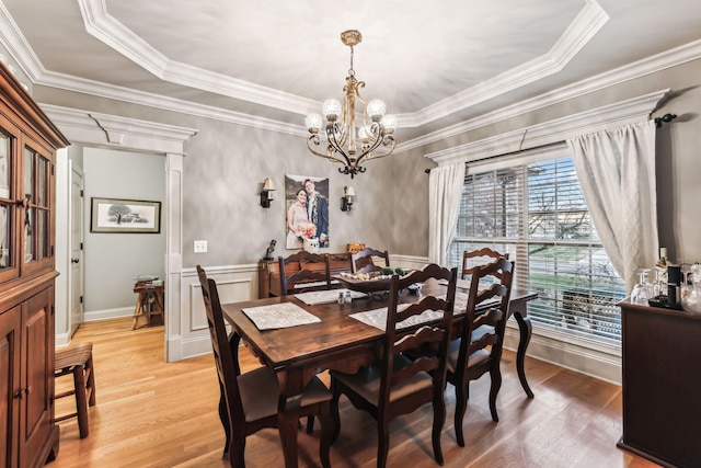 dining area with a raised ceiling, a wealth of natural light, crown molding, and wood-type flooring