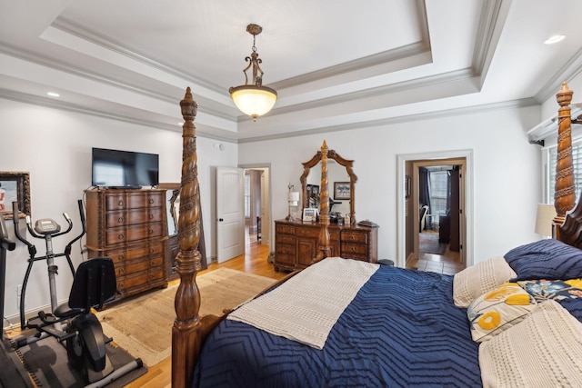 bedroom with hardwood / wood-style floors, ornamental molding, and a tray ceiling