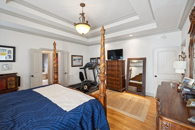 bedroom with a tray ceiling, crown molding, and light wood-type flooring