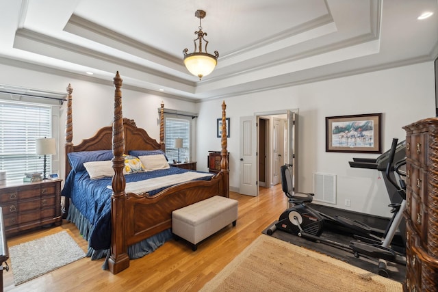 bedroom featuring a tray ceiling, light hardwood / wood-style floors, and ornamental molding