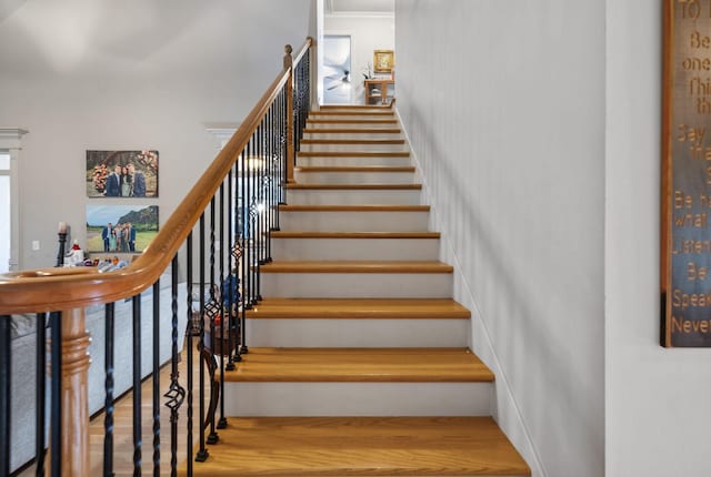 staircase with wood-type flooring and crown molding