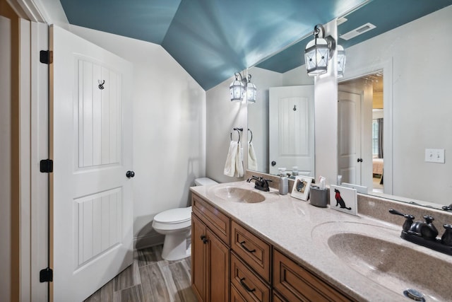 bathroom with toilet, wood-type flooring, vanity, and vaulted ceiling