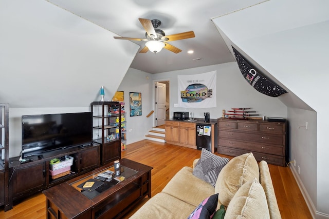 living room featuring ceiling fan, light hardwood / wood-style floors, and vaulted ceiling