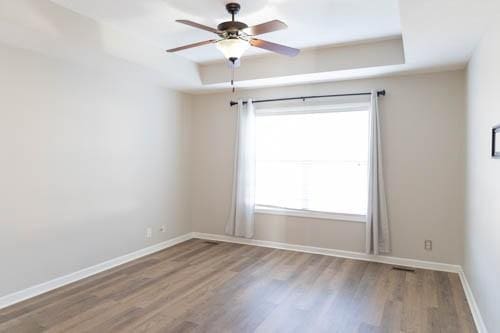 spare room with ceiling fan, plenty of natural light, and wood-type flooring