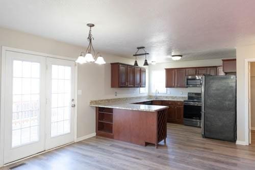 kitchen with kitchen peninsula, stainless steel appliances, decorative light fixtures, a chandelier, and light hardwood / wood-style floors