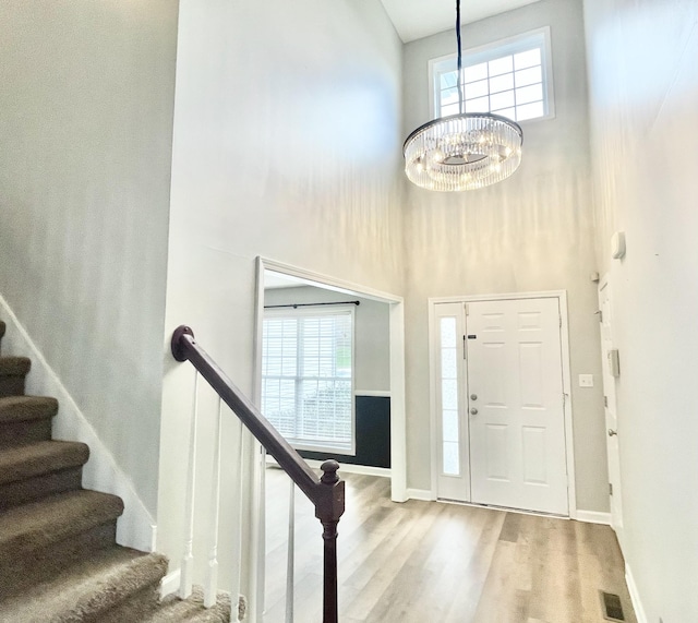 entryway featuring hardwood / wood-style floors, an inviting chandelier, and a high ceiling