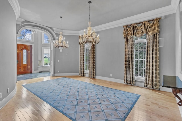 entrance foyer featuring light hardwood / wood-style floors, ornamental molding, and an inviting chandelier