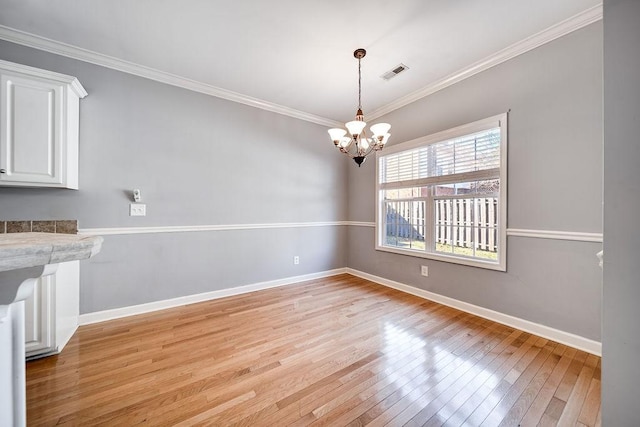 unfurnished dining area featuring a notable chandelier, light hardwood / wood-style floors, and ornamental molding