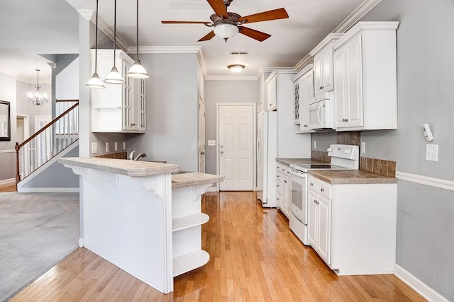 kitchen featuring kitchen peninsula, a kitchen breakfast bar, white appliances, decorative light fixtures, and white cabinets