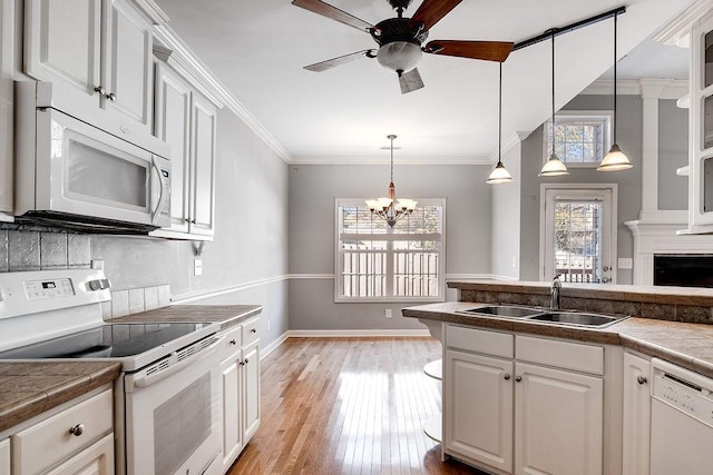 kitchen with pendant lighting, white appliances, sink, light wood-type flooring, and white cabinetry