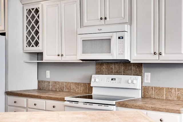 kitchen featuring white appliances, white cabinetry, and backsplash