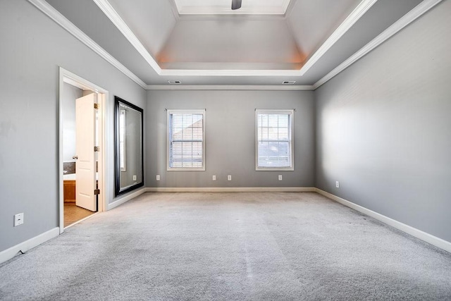 unfurnished bedroom with ensuite bathroom, a raised ceiling, ornamental molding, and light colored carpet