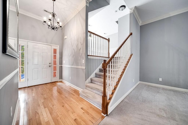 entrance foyer with light hardwood / wood-style flooring, an inviting chandelier, a high ceiling, and ornamental molding