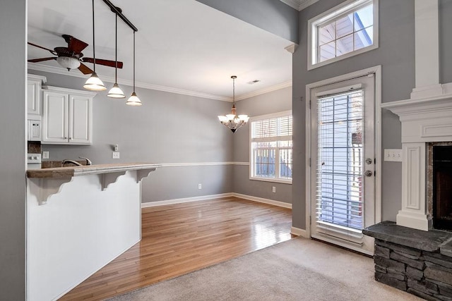 kitchen with a kitchen breakfast bar, crown molding, white cabinets, light hardwood / wood-style floors, and hanging light fixtures