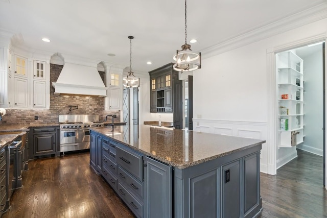 kitchen with premium range hood, range with two ovens, hanging light fixtures, a center island, and white cabinets