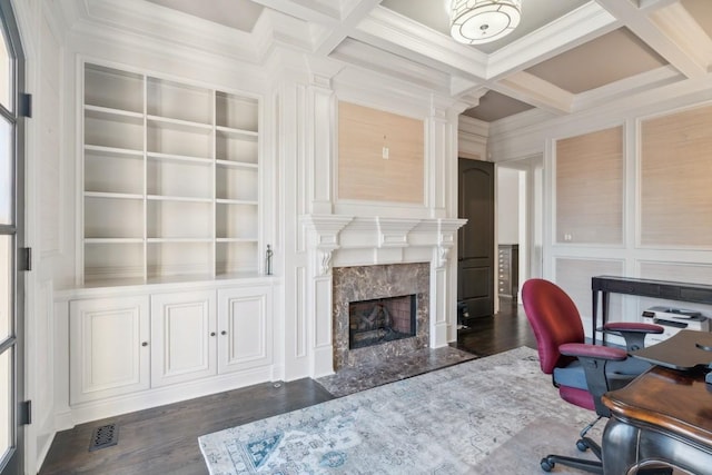 office area featuring built in shelves, beam ceiling, a high end fireplace, ornamental molding, and coffered ceiling