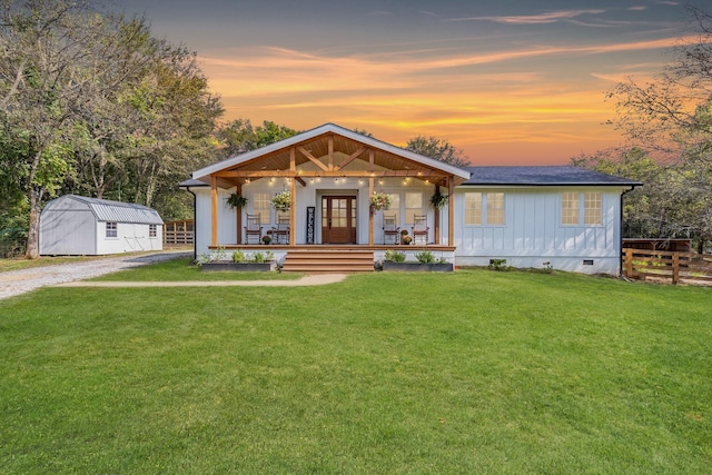 view of front of house featuring a lawn, a storage unit, and covered porch