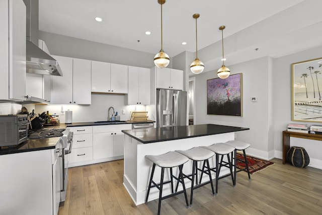 kitchen with light wood-type flooring, stainless steel appliances, a kitchen island, sink, and white cabinetry