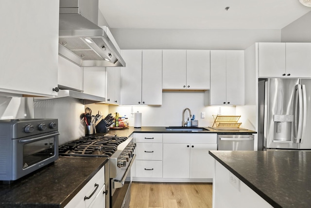 kitchen with sink, white cabinets, stainless steel appliances, and wall chimney range hood