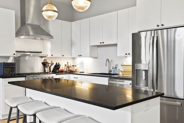 kitchen with white cabinets, sink, stainless steel appliances, and wall chimney range hood