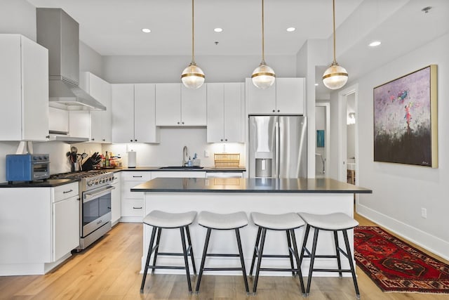 kitchen with white cabinetry, stainless steel appliances, and wall chimney range hood