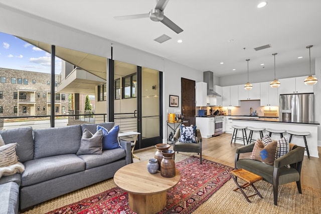 living room featuring ceiling fan, light hardwood / wood-style flooring, and sink