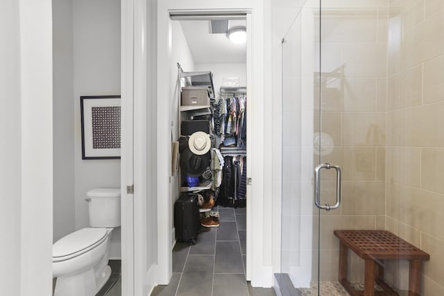 bathroom featuring tile patterned flooring, toilet, and an enclosed shower