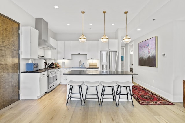 kitchen with white cabinets, sink, stainless steel appliances, and wall chimney range hood