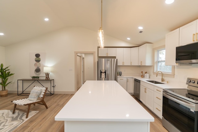 kitchen featuring hanging light fixtures, stainless steel appliances, vaulted ceiling, white cabinets, and light wood-type flooring