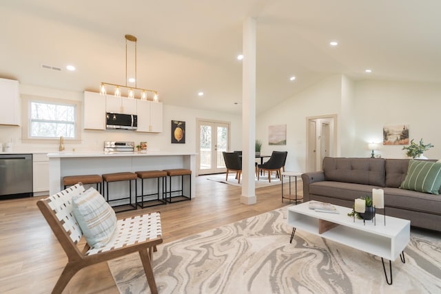 living room with sink, high vaulted ceiling, and light hardwood / wood-style flooring