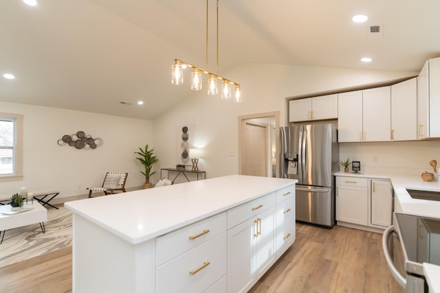 kitchen featuring range, vaulted ceiling, white cabinets, stainless steel fridge with ice dispenser, and a center island