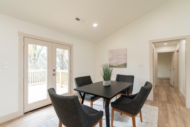 dining room featuring light wood-type flooring, high vaulted ceiling, and french doors