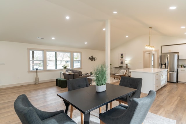 dining space with light hardwood / wood-style flooring and vaulted ceiling