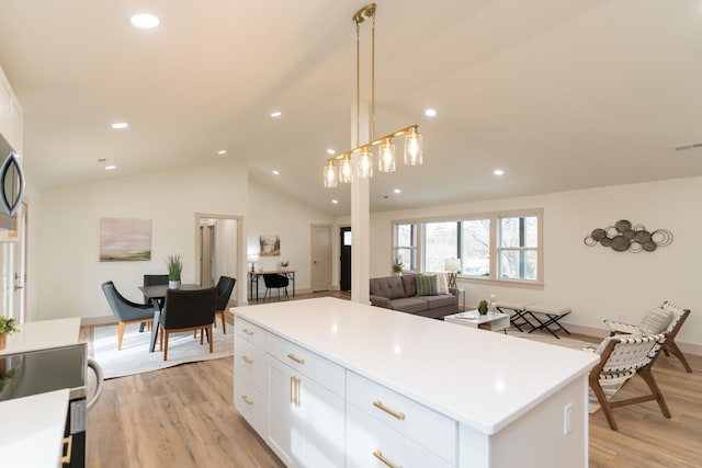 kitchen with light wood-type flooring, decorative light fixtures, a center island, white cabinetry, and lofted ceiling