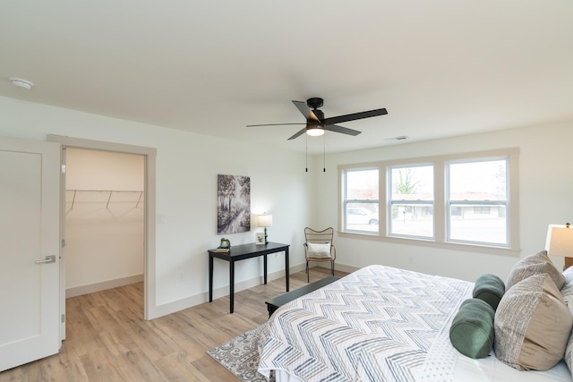 bedroom with a closet, light hardwood / wood-style flooring, a spacious closet, and ceiling fan