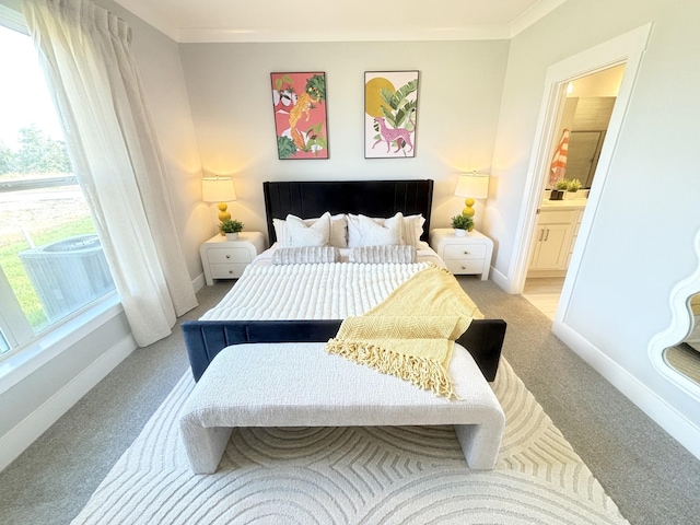 carpeted bedroom featuring ensuite bath, crown molding, and multiple windows